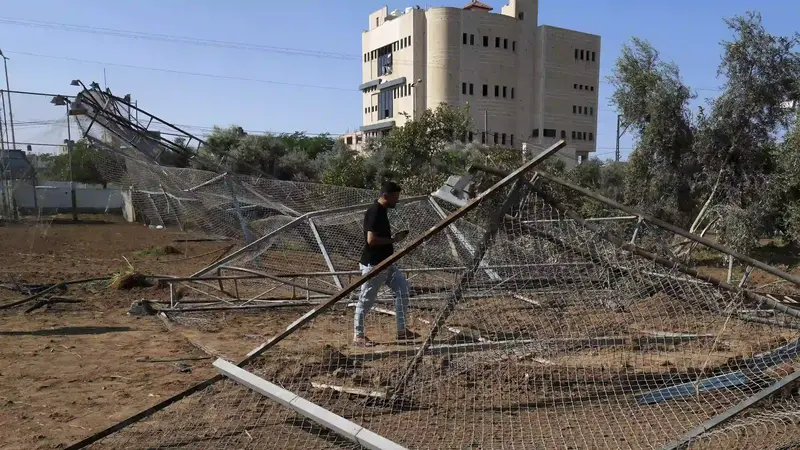 Seorang pemuda memeriksa pagar lapangan sepak bola dan pohon zaitun yang hancur akibat serangan udara Israel, di kamp pengungsi Maghazi, Jalur Gaza tengah, Jumat, 4 November 2022. (AP Photo/Adel Hana) Palestina
