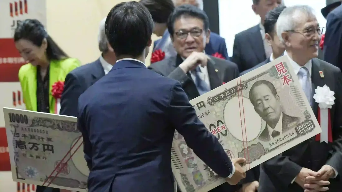 Seorang staf memegang salinan uang kertas 10.000 yen baru dan lama yang diperbesar setelah "Upacara Penyerahan Uang Kertas 10.000 Yen" di Bursa Saham Tokyo pada hari Rabu, 3 Juli 2024, di Tokyo. (AP Photo/Eugene Hoshiko) yen