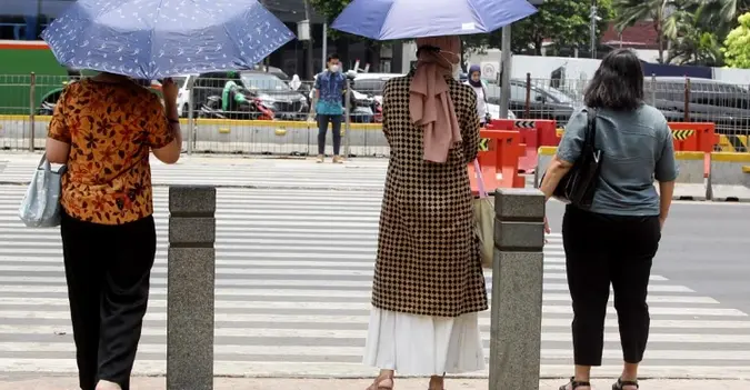 Ilustrasi warga yang memakai payung untuk melindungi dari paparan sinar matahari. cuaca panas