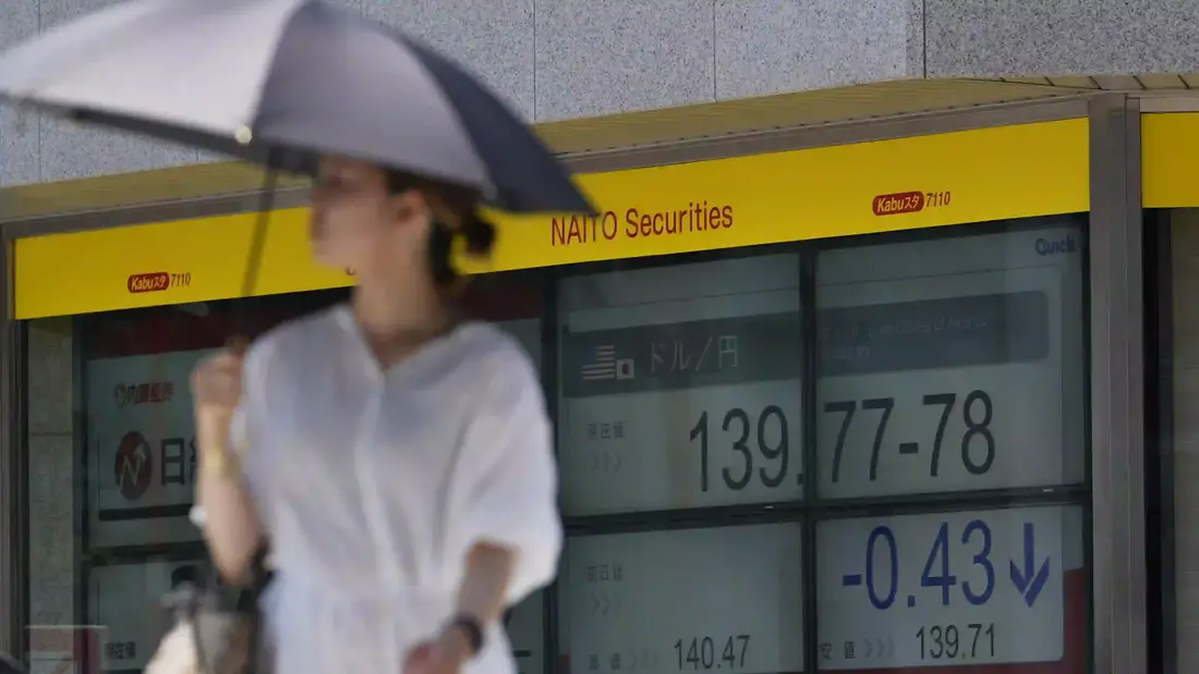 Seorang wanita berjalan menyeberangi persimpangan di dekat monitor yang menampilkan nilai tukar yen Jepang terhadap dolar AS di sebuah perusahaan sekuritas di Tokyo, Kamis, 27 Juli 2023. (AP Photo/Hiro Komae)